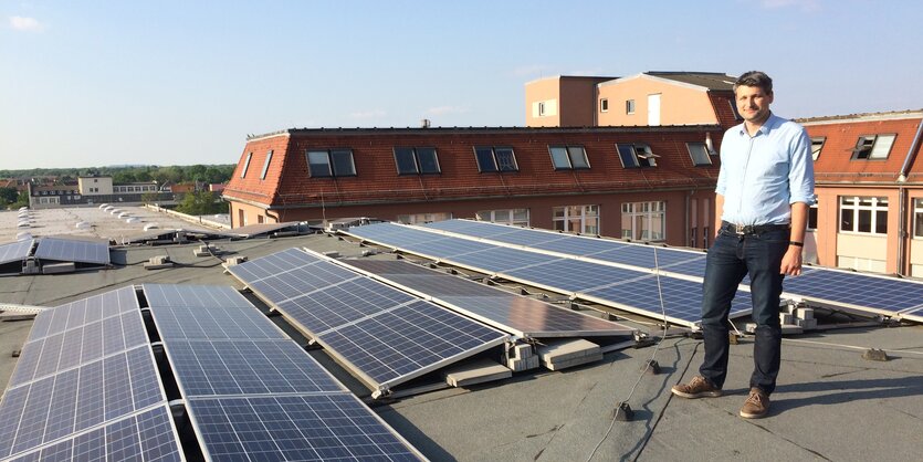 Ein Mann steht auf einem Dach mit einer Solaranlage.