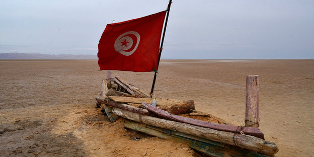 Bootartige Struktur auf Sand mit tunesischer Flagge