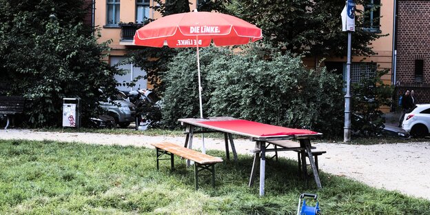 ein Tisch und Bänke und ein Sonnenschirm mit Linkspartei-Logo