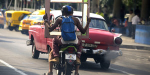 Zwei Männer auf einem Motorrad transporieren einen Bilderrahmen in Kubas Hauptstadt Havanna.