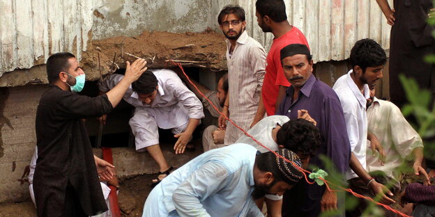 Pakistansche Textilarbeiter in einem ausgebrannten Gebäude