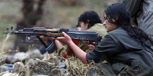Eine kurdische Frau der PKK zielt mit einem Gewehr.