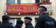 Polizisten stehen vor einem Haus, an der Fassade hängt ein Transparent mit der Aufschrift "Unser Nachbar Kalle bleibt"