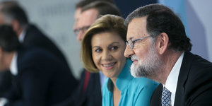 Rajoy guckt sinnend vor sich hin, eine Frau guckt lächelnd zu ihm rüber