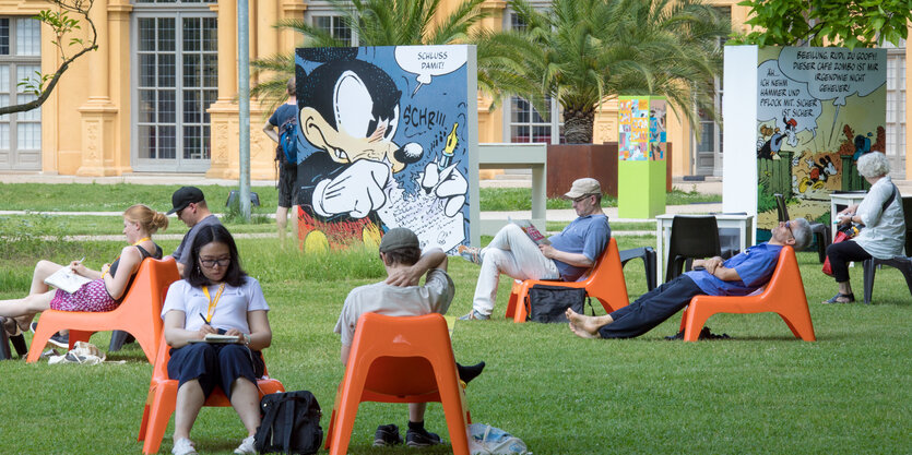 Besucher des Comicsalons Erlangen sitzen auf der Schloßwiese bei schönem Wetter