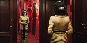 Eine Frau im eleganten Kleid vor einem Spiegel