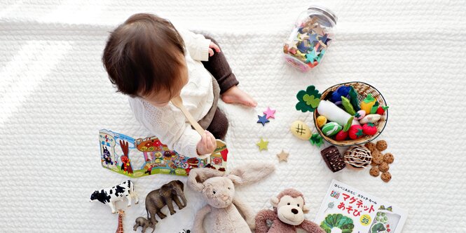 Kleinkind inmitten bunter Spielsachen