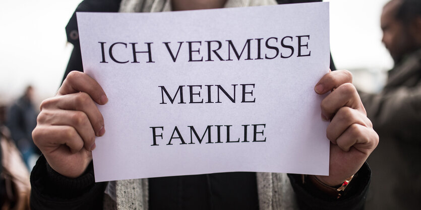 Jemand hält ein Schild hoch, auf dem "Ich vermisse meine Familie" steht