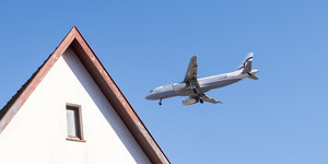 Ein Flugzeug fliegt tief über ein Wohnhaus