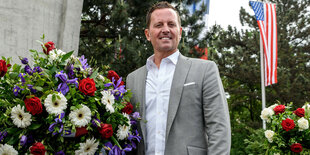 Botschafter Grenell steht neben Blumen