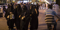 In der Abenddämmerung geht eine Gruppe von verschleierten Frauen eine belebte Straße entlang