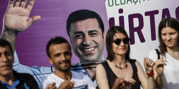 Menschen tanzen vor einem Plakat des inhaftierten Präsidentschaftskandidaten Selahattin Demirtas