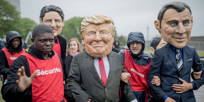 Menschen mit großen Gesichtsmasken gehen neben Menschen mit roten Westen