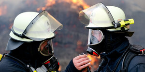 Zwei voll ausgerüstete Feuerwehrmänner blicken sich an