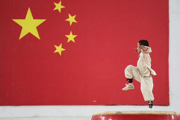 Ein Shaolin-Schüler performt vor der chinesischen Flagge