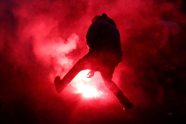 Ein Protestler zündet eine Leuchtbombe