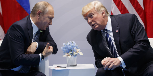 Wladimir Putin und Donald Trump sitzen nebeneinander und reden miteinander
