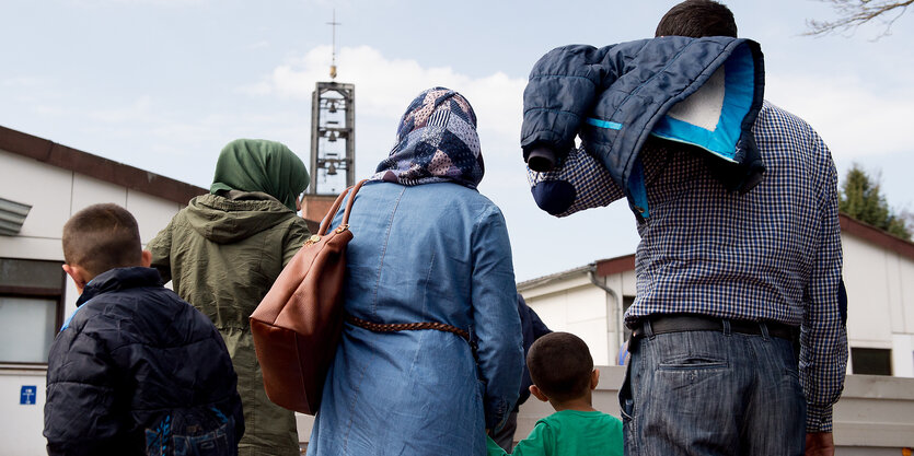 Syrische Flüchtlinge ziehen mit Gepäck ins Grenzdurchgangslager Friedland ein.