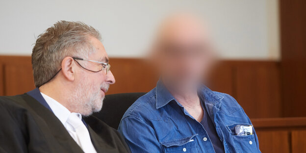 Der Angeklagte sitzt neben seinem Anwalt, sein Gesicht ist verpixelt