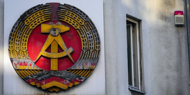 Das Staatswappen der DDR am Checkpoint Charlie