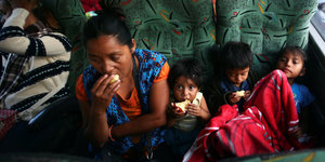 Eine lateinamerikanische Frau und drei Kinder sitzen in einem Bus und essen