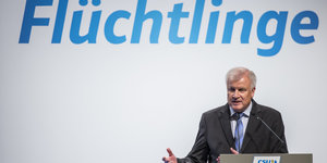 Innenminister Horst Seehofer stitzt unter dem Schriftzug "Flüchtlinge"