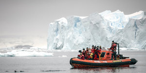 Menschen in einem Greenpeace-Boot. Im Hintergrund sieht man Eisberge