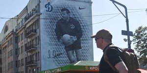 Ein mann schaut auf ein Wandbild, auf dem ein Fußballer abgebildet ist
