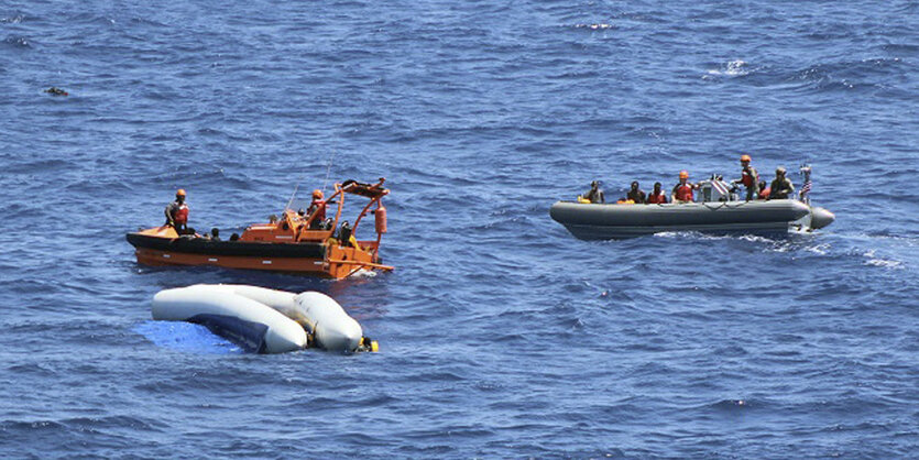 Drei Boote schwimmen im Meer, eines davon ist umgekippt