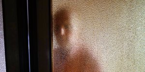 Ein Mann hinter einer milchigen Glastür