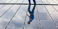 Ein Mann läuft auf einem Dach mit Solarzellen