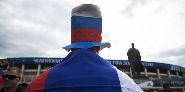 Ein russischer Fan trägt Hut und Flagge in Landesfarben