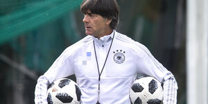 Trainer Joachim Löw trägt unter jedem Arm einen Ball
