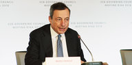 Mario Draghi sitzt vor einem Mikrofon