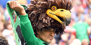 Ein mexikanischer Fan steht im Stadion mit einem Adler auf dem Kopf und schaut melancholisch drein