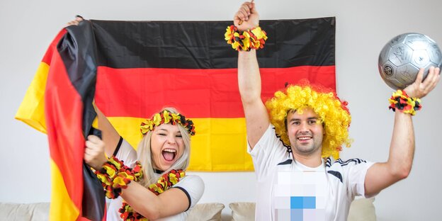 Zwei Menschen jubeln mit Fanartikeln in Deutschlandfarben