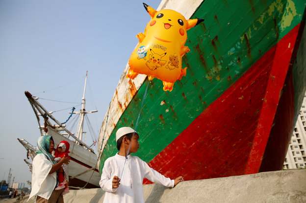 Ein Junge vor einem Boot hält einen Pikachu-Luftballon