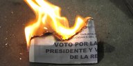 Ein brennender Wahlzettel liegt auf dem Boden