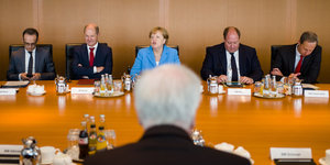 Merkel, Scholz, Maas und andere Politiker sitzen an einem Tisch, Seehofer sitzt ihnen gegenüber (man sieht den Hinterkopf)