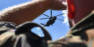 Ein Mann Mann hält sich die Hand an die Stirn und blickt einem Hubschrauber entgegen