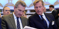 Ex-EU-Digitalkommissar Günther Oettinger und BDZV-Präsident Mathias Döpfner stzen nebeneinander beugen sich gemeinsam über ein Papier.
