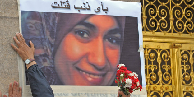 Vor dem Rathaus in Dresden kleben zwei Männer ein Foto der am 01.07.2009 im Dresdner Landgericht erstochenen Ägypterin Marwa El-Sherbini an die Wand