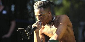 XXXTentacion mit freiem Oberkörper und einem Miko in der Hand