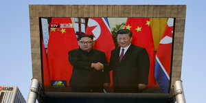 Ein riesiger Bildschirm, auf dem das Treffen von Kim Jong Un, Machthaber von Nordkorea, und Xi Jinping, Präsident von China, zu sehen ist
