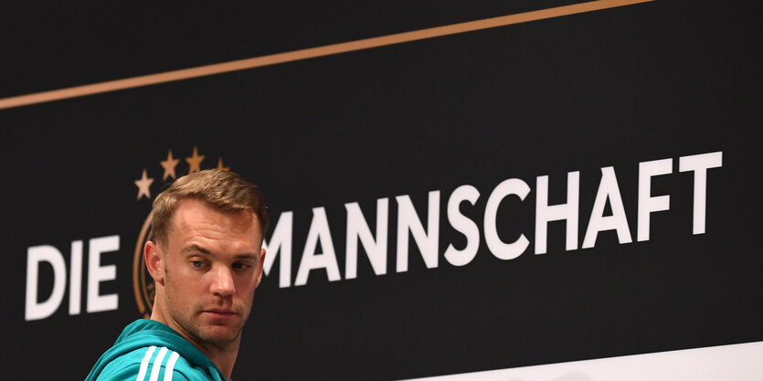 Manuel Neuer kommt zur Pressekonferenz in Watutinki. Er steht vor einem Transparent mit der Aufschrift: Die Mannschaft.