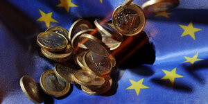 Euro-Münzen fallen auf einen EU-Fahne