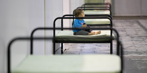 In Hangar 2 des ehemaligen Flughafen Tempelhof: Kleines Kind sitzt auf einem spartanischen Bett