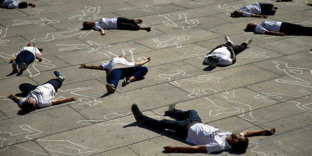 Menschen liegen wie tot auf einem Platz in Madrid, um am Weltflüchtlingstag für Flüchtlinge zu protestieren