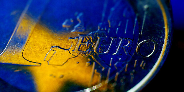 Die Fahne der europäischen Union spiegelt sich in einer Ein-Euro-Münze
