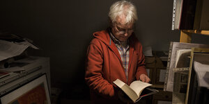 Grauhaariger Mann blättert ein Buch auf